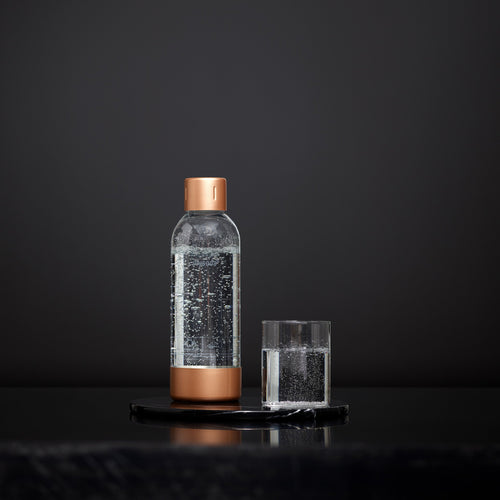 A copper Mysoda premium bottle and a glass of water in front of black background #väri_copper